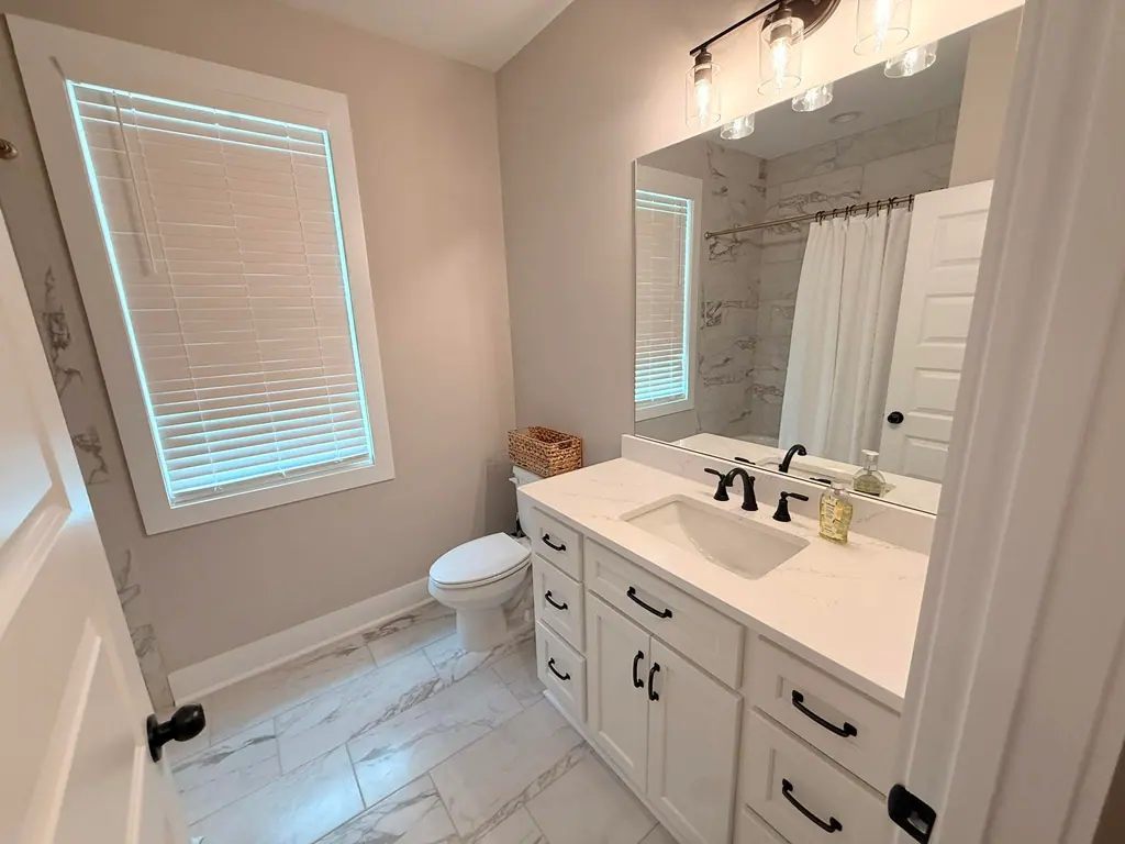 Bathroom with a white shaker vanity, black fixtures and marble-look tile, freshly cleaned