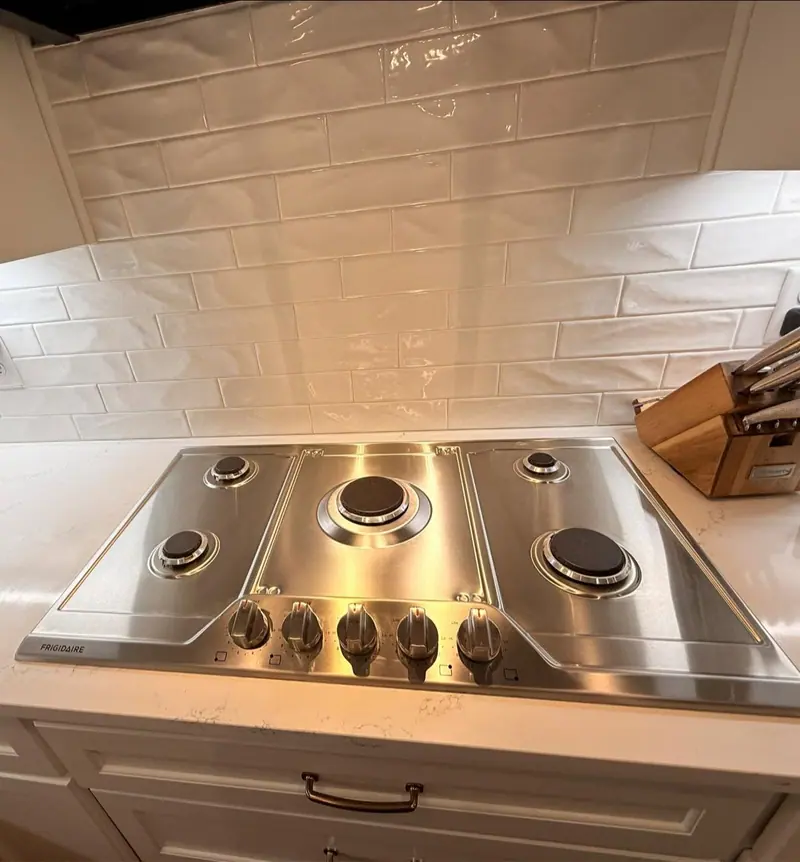Stainless gas cooktop wiped clean under a white subway tile backsplash