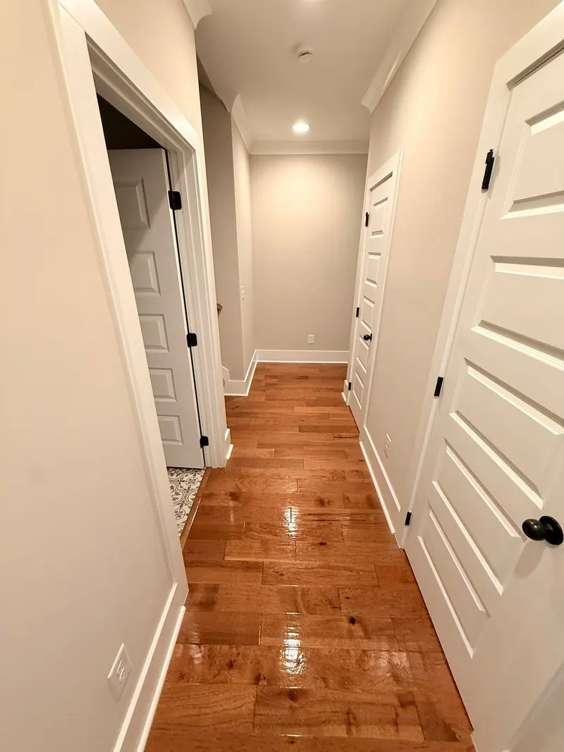 Long hallway with glossy hardwood floors and white doors after cleaning