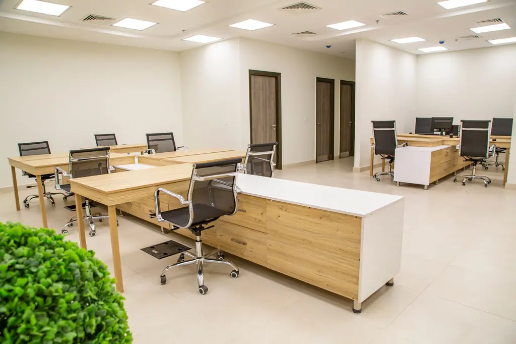 Clean open-plan office with light oak desks and black chairs